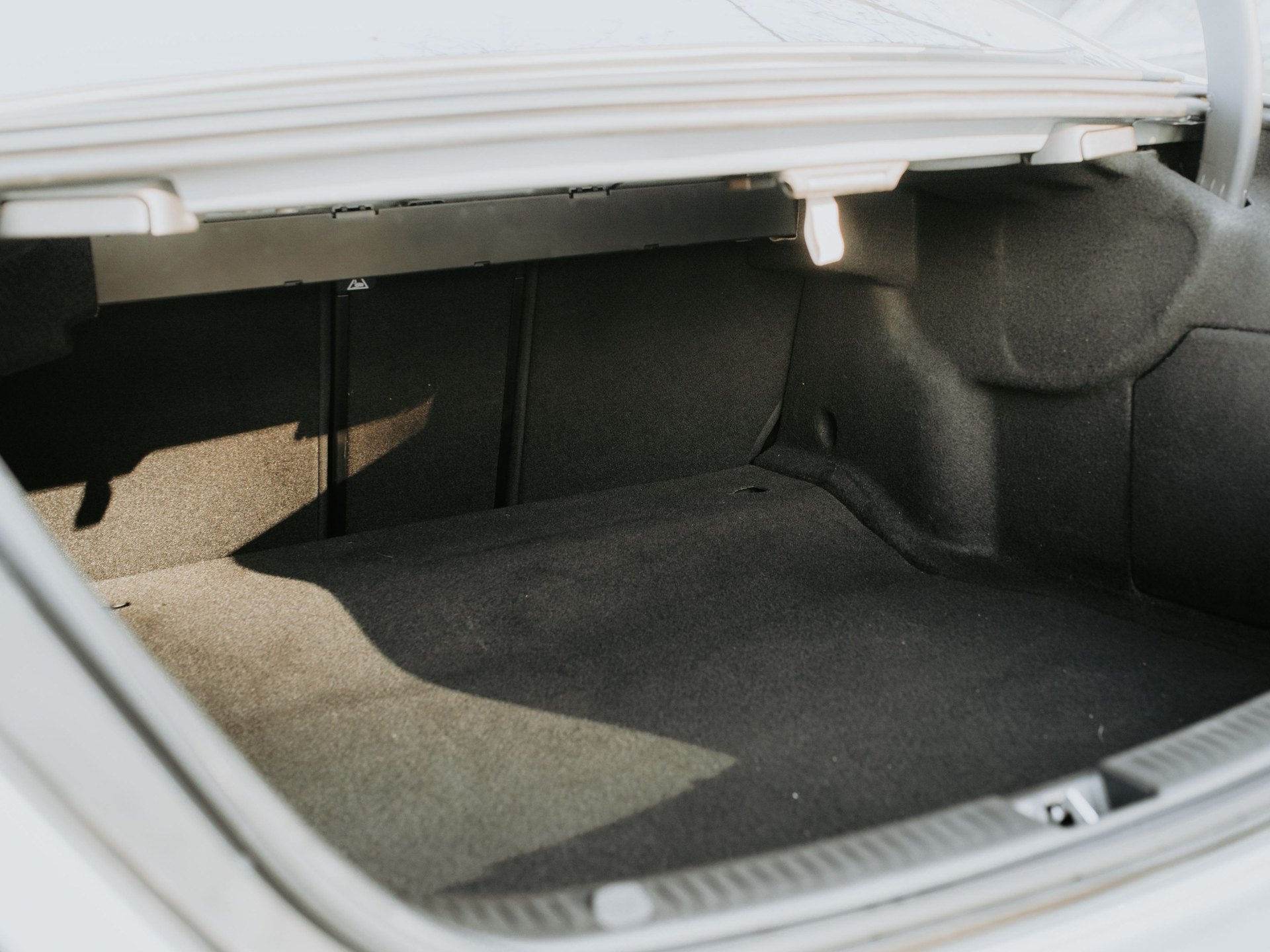 Empty sedan trunk with felt floor beneath the package tray — representative image